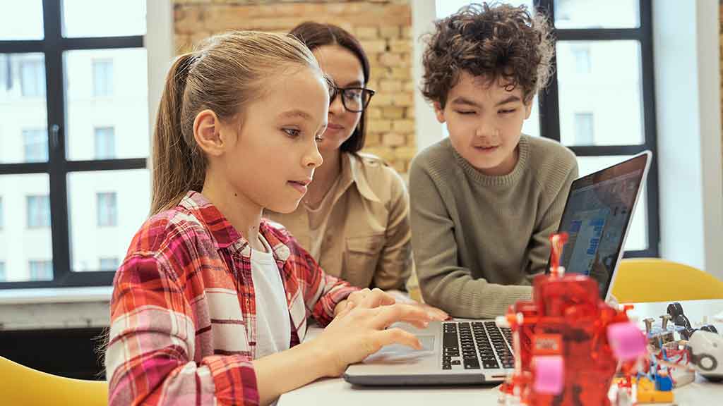 Enfants travaillant ensemble sur un ordinateur portable dans une salle de classe