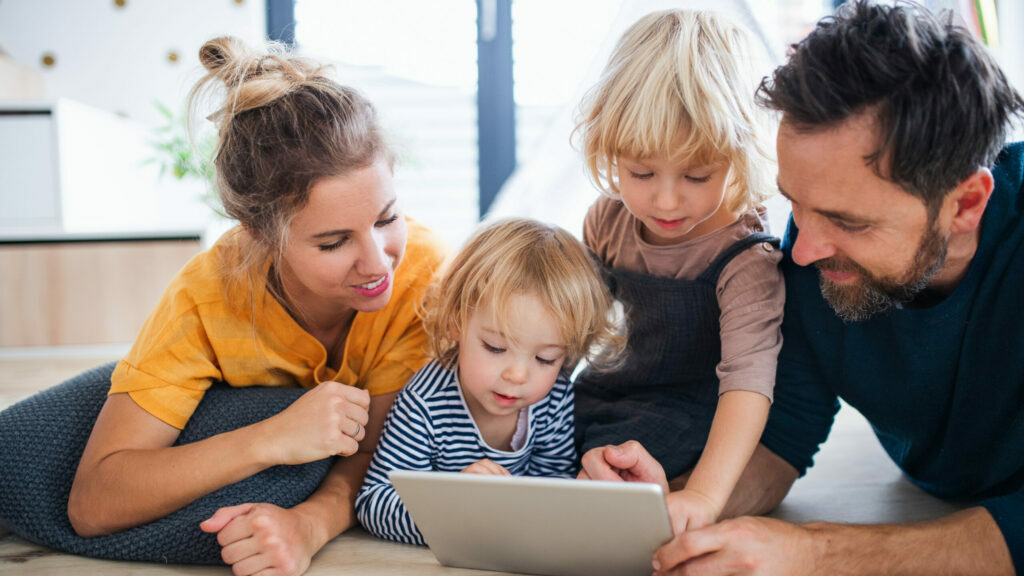 Parents à la maison avec de jeunes enfants jouant ensemble sur une tablette